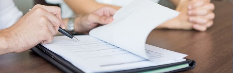 Uma pessoa aponta a outra o local onde ela deve assinar, em um contrato