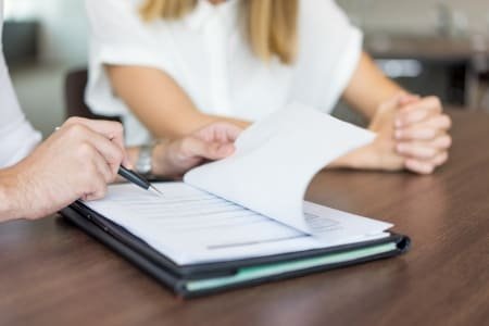Uma pessoa aponta a outra onde ela deve assinar em um contrato
